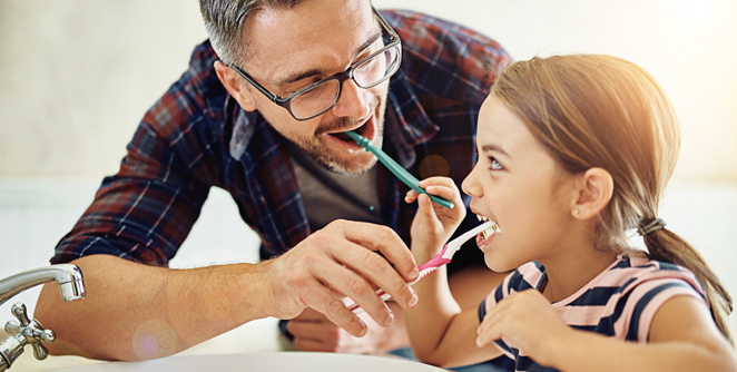 White father and daughter helping to brush each other's teeth for good oral health