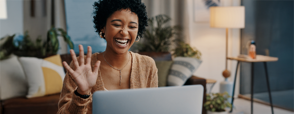 woman smiling at laptop in a living room background